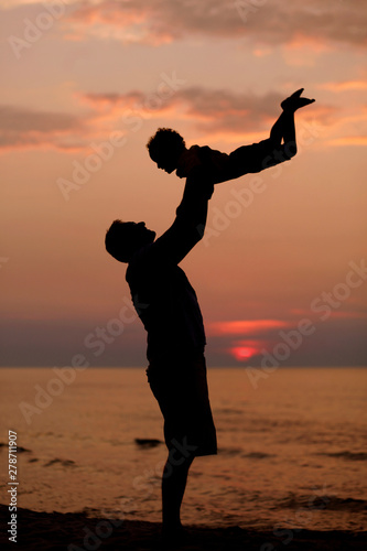 Daddy and son playing at the beach at sunset, leisure and vacation time