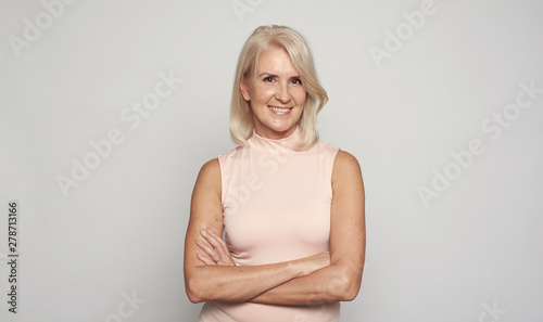 Beautiful 50 years lady with hands folded is smiling. Isolated photo
