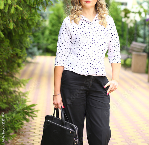 stylish business woman walking down the street in summer with a bag photo