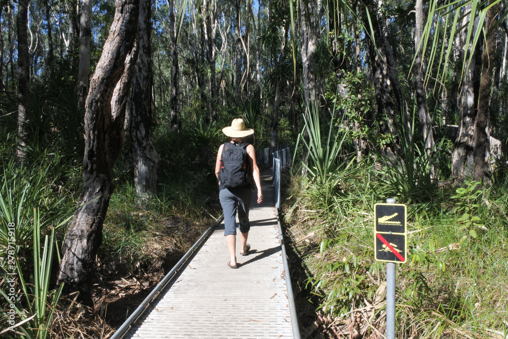 Australian woman tourist passing by a beware for the crocodiles sign Northern Territory Australia