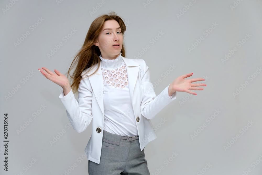 Portrait to the waist of a young pretty brunette girl woman with beautiful long hair on a white background in a white jacket and gray pants. Talks, smiles, shows hands with emotions in various poses. Portrait to the waist of a young pretty brunette girl woman with beautiful long hair on a white background in a white jacket and gray pants. Talks, smiles, shows hands with emotions in various poses.