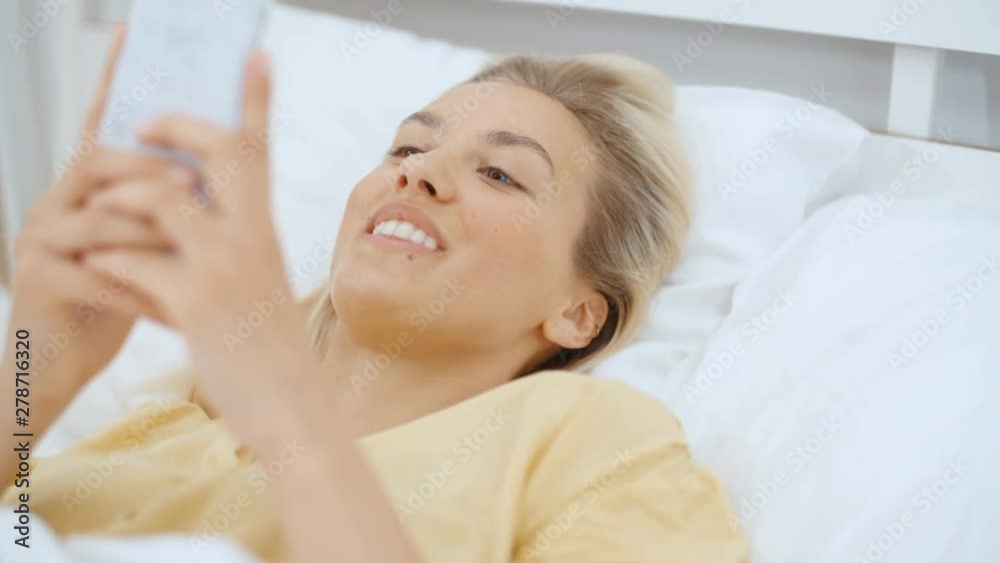 Beautiful blonde woman wearing pajama using phone in her bedroom. Beautiful blonde woman wearing pajama using phone in her bedroom.