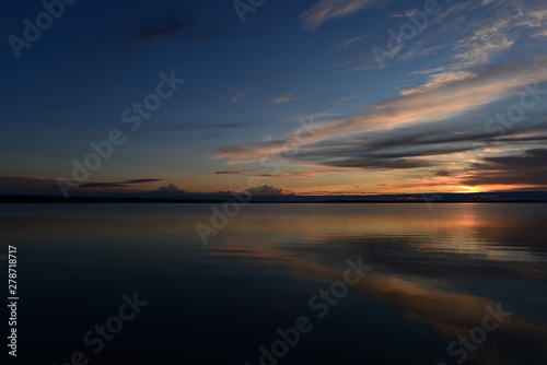 Sunlight and shadows at sunset on the lake water surface under a clear blue sky © yarvin13