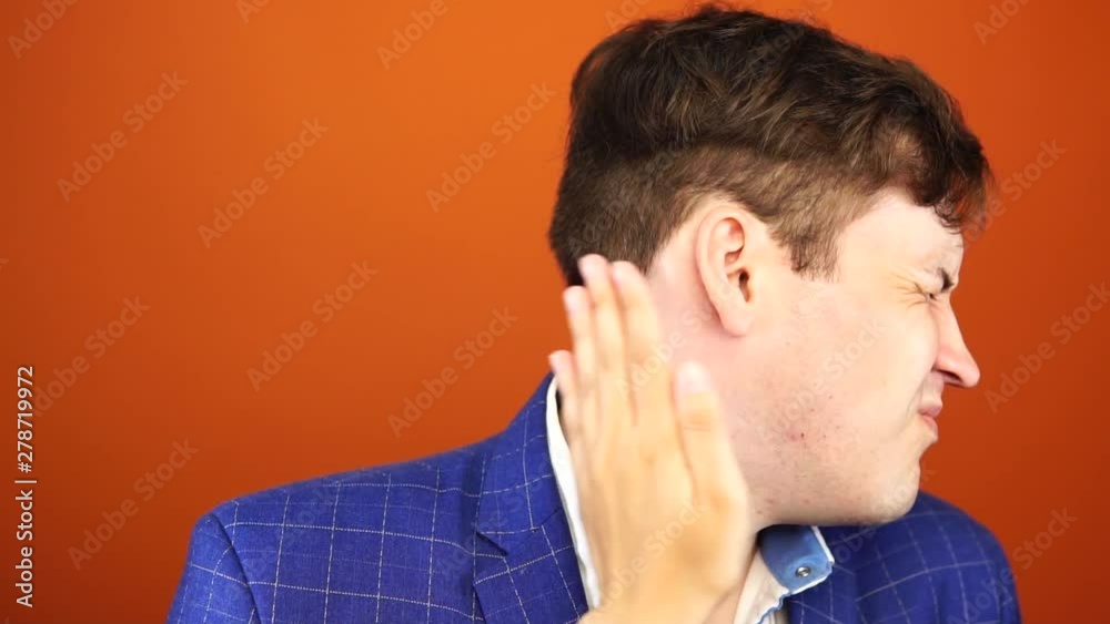 Man getting slapped on orange background. Unhappy scared man getting slapped standing on orange background Man getting slapped on orange background. Unhappy scared man getting slapped standing on orange background