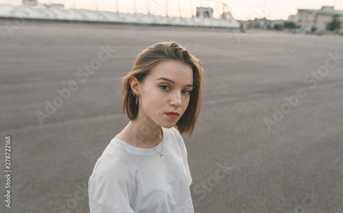 Evening portrait of an attractive girl with a serious face looking into the camera. A beautiful, well-dressed girl wearing casual clothing poses to the camera. © bodnarphoto