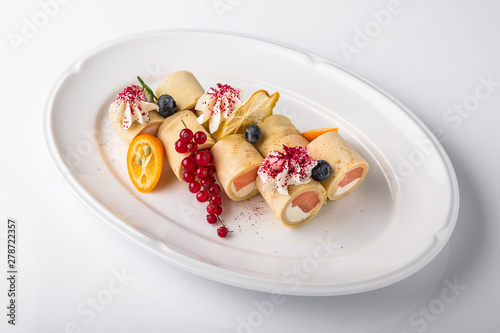 Pancakes rolls stuffed with salmon, spinach, Philadelphia cheese. Banquet festive dishes. Gourmet restaurant menu. White background.