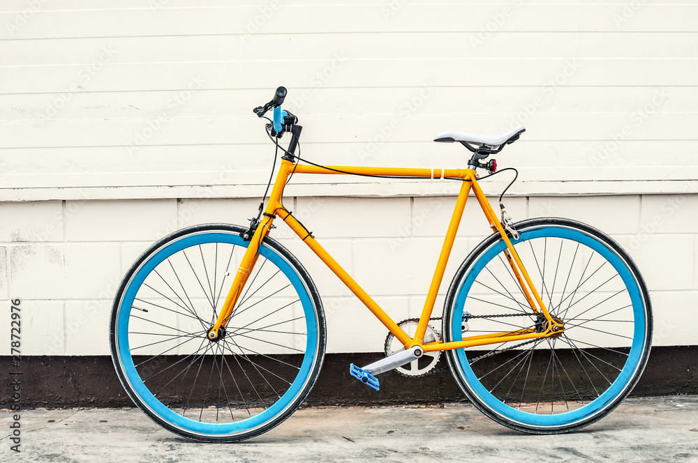 Old yellow fixed gear bicycle on white wall background