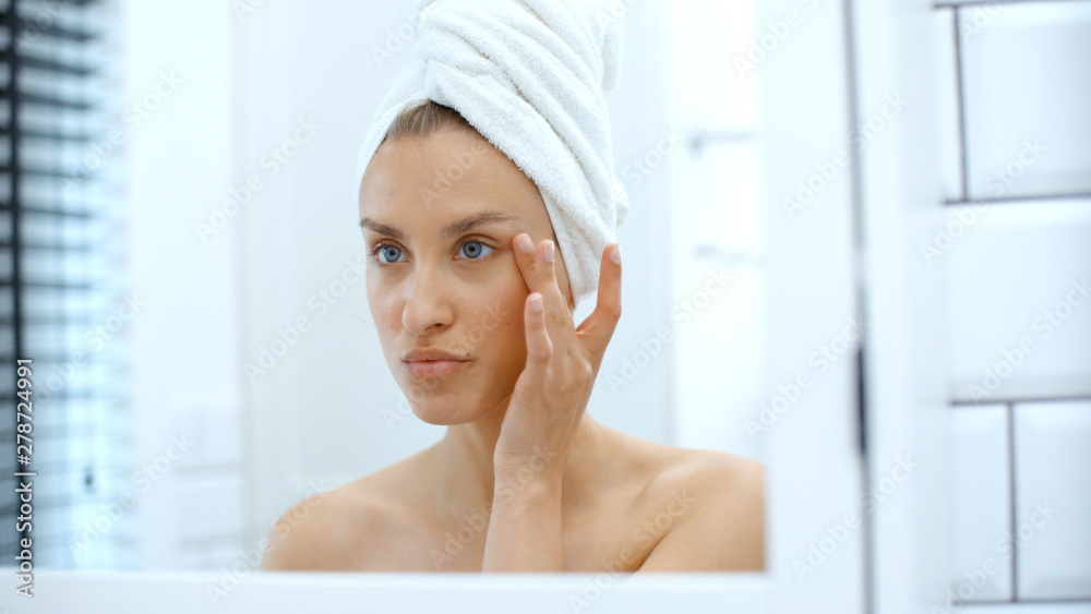 Closeup of beautiful young woman examining herself in front of mirror. Closeup of beautiful young woman examining herself in front of mirror.
