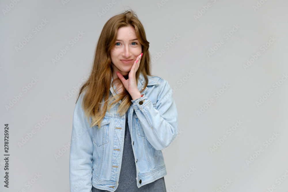 Portrait to waist of a young pretty brunette girl woman with beautiful long hair on a white background in a jacket from jeans. He talks, smiles, shows his hands with emotions in various poses. Portrait to waist of a young pretty brunette girl woman with beautiful long hair on a white background in a jacket from jeans. He talks, smiles, shows his hands with emotions in various poses.