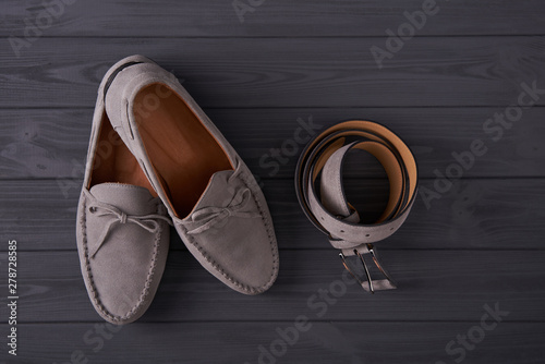Elegant suede man's moccasins shoes with a belt over grey planks photo