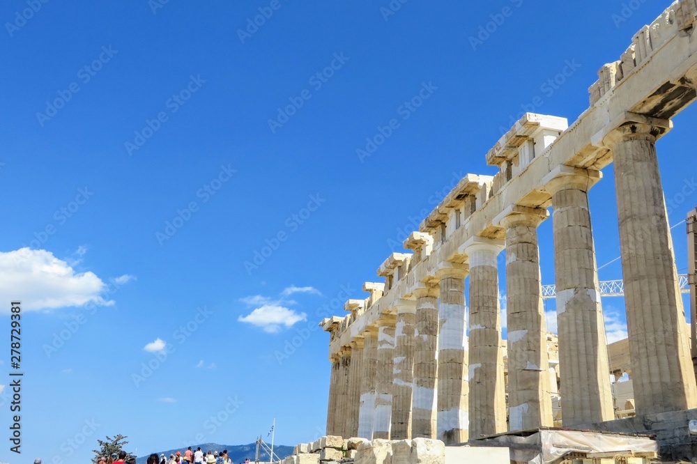 Obraz premium An interesting view of the Parthenon columns facing a blue sky atop the Acropolis in Greece. The parthenon has Doric columns made of marble extending around the periphery of the entire structure