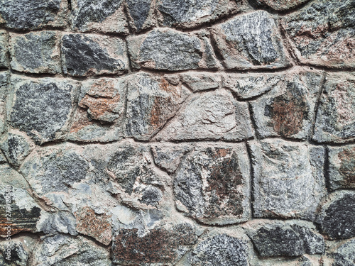 Old stone of wall texture. Lots of granite cobblestones. Close up, copy space.