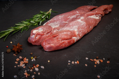 two long pieces of raw marbled meat with green rosemary