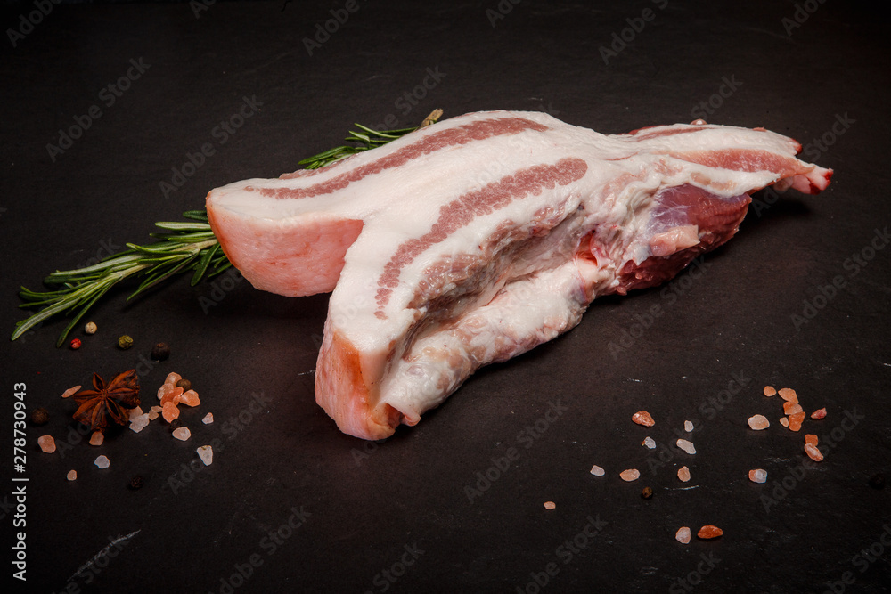 big piece of raw pork fat with meat served with rosemary