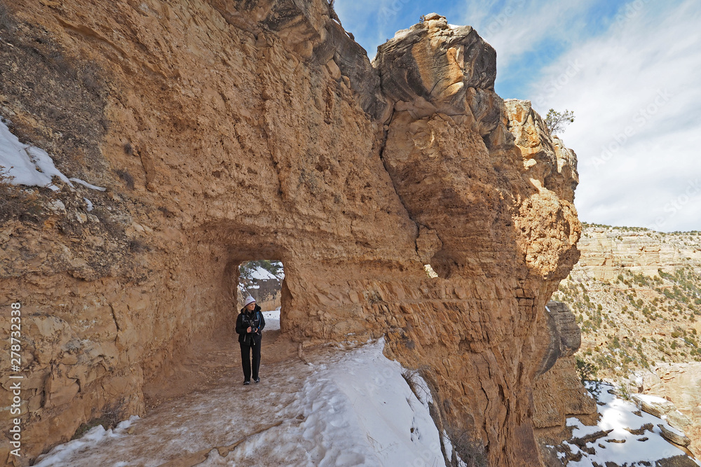 Woman hiking on a snowy Bright Angel Trail in Grand Canyon National Park, Arizona, in winter.