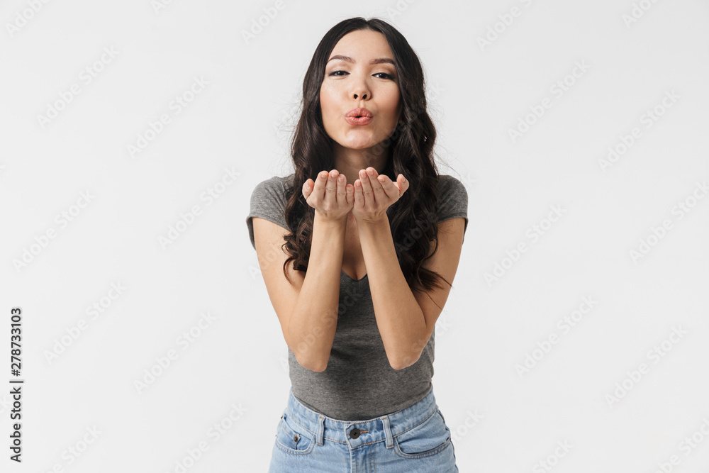 Beautiful emotional young woman posing isolated over white wall background blowing kisses. Beautiful emotional young woman posing isolated over white wall background blowing kisses.