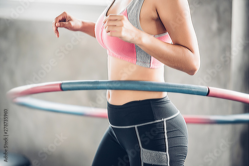 Asian woman excercise with hula hoop in the gym.