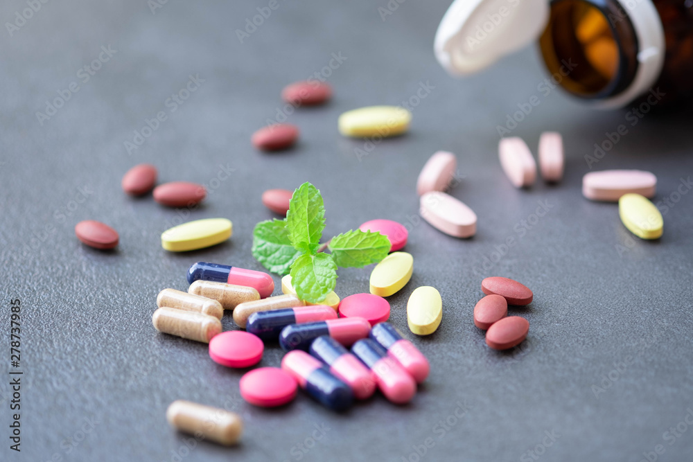 Assorted pharmaceutical medicine and herbal arganic medicine capsules on table dark background.