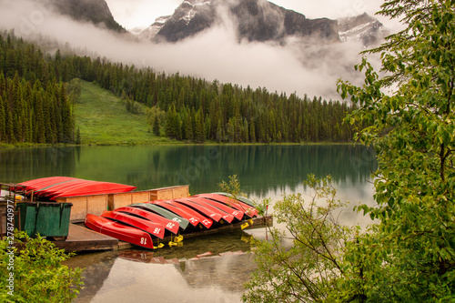 Red canoe boats stacked on dock at the lake