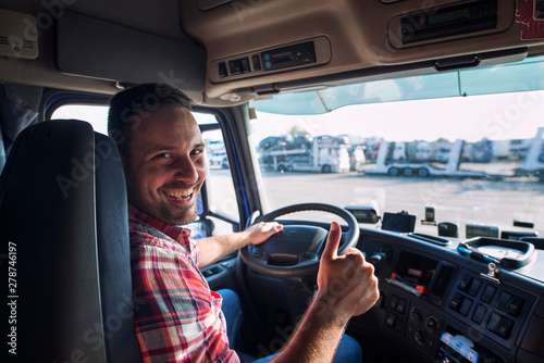 Portrait of truck driver sitting in his truck holding thumbs up. Transportation and trucking services. photo