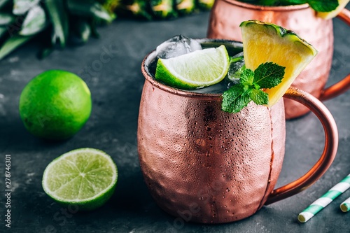 Photography Iced Cold Moscow Mule cocktail with lime and pineapple on dark background