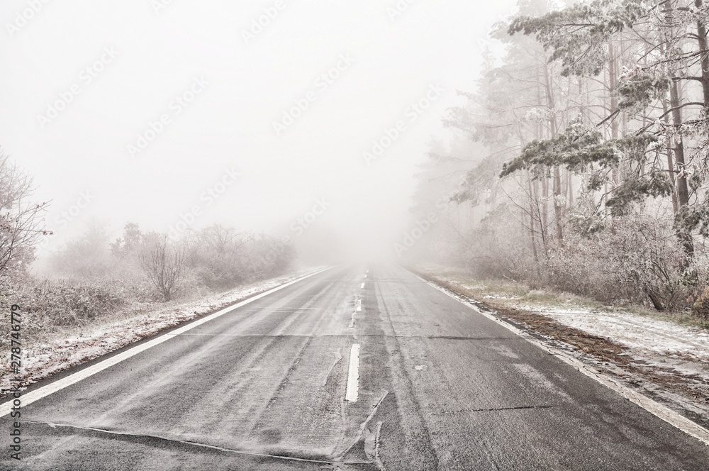 Straight empty wet asphalt road during foggy conditions Straight empty wet asphalt road during foggy conditions