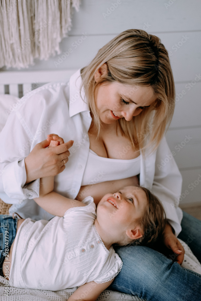 My daughter is in the lap of the mother in the bright and cosy bedroom. The woman has blond hair, the baby has beautiful blue eyes. Motherhood, love concept. My daughter is in the lap of the mother in the bright and cosy bedroom. The woman has blond hair, the baby has beautiful blue eyes. Motherhood, love concept.