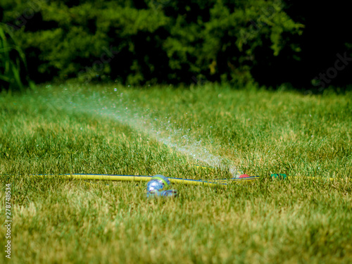 sprinkler is watering field with drops of water