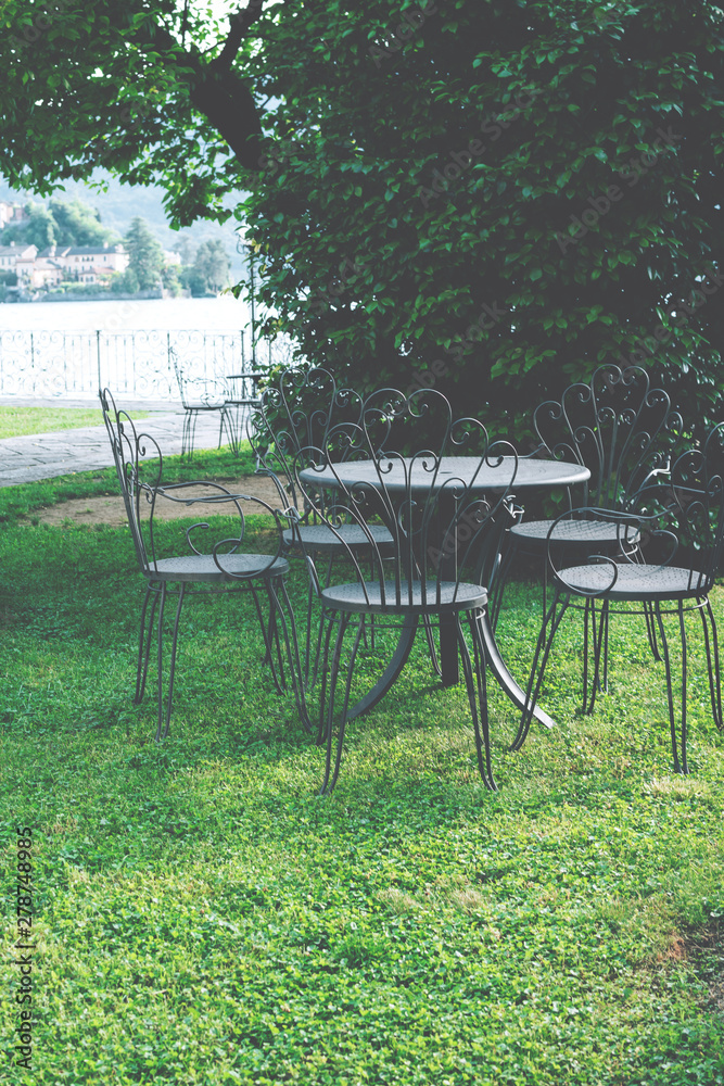Vintage metallic (iron) chairs and table in the garden near the lake. Rustic style. 
