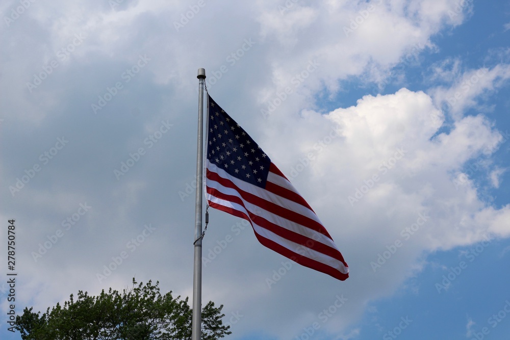 A view of the american flag and the white clouds and sky. A view of the american flag and the white clouds and sky.