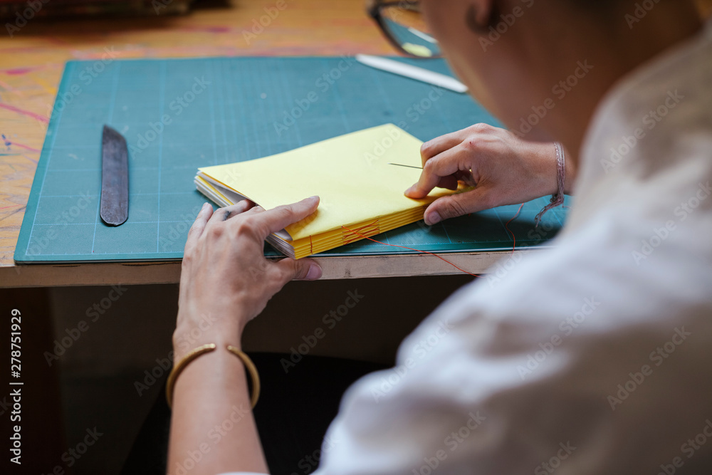 Young adult woman making a notebook in his laboratory - Artisan at work Young adult woman making a notebook in his laboratory - Artisan at work