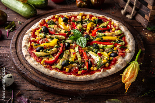 Tasty hot italian pizza Vegetarian pizza with zucchini, pepper, mushrooms, cheese, olives, basil, tomatoes, sauce on old wooden table. Pizzeria menu. Concept poster for Restaurants
