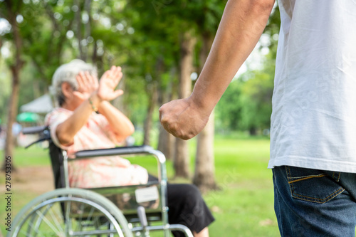 Asian elderly woman in wheelchair were physically abused,attacking in outdoor,stop physical abuse senior people,angry man or caregiver raised punishment fist,stop violence and aggression concept