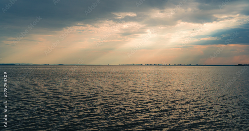 Fototapeta premium Seascape. Evening overcast sky and the rays of the sun.