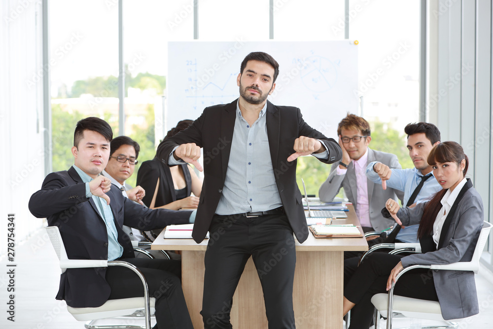 caucasian boss businessman showing thumb down or dislike with unhappy face with unsuccess multiethnic business team and business graph background caucasian boss businessman showing thumb down or dislike with unhappy face with unsuccess multiethnic business team and business graph background