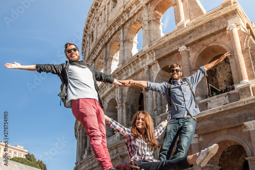 Photography Three happy young friends tourists standing in front of colosseum in rome posing