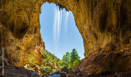 Inside Tonto Natural Bridge in the mountains of Arizona looking out from behind a waterfall. photo