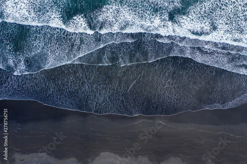 Aerial view of Atlantic ocean waves washing black sandy beach