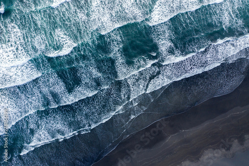 Платно Aerial view of Atlantic ocean waves washing black sandy beach
