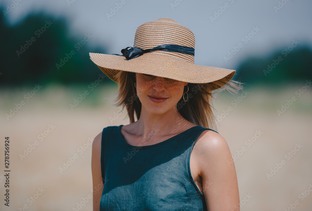 Woman in a straw hat that hides her eyes against the background of the nature