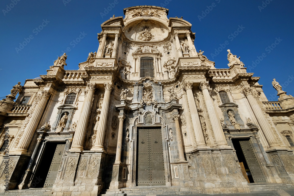 Exterior facade of Cathedral Catholic Church of Saint Mary front view against blue sky background, ancient architecture religious monument in Murcia city,  Spain