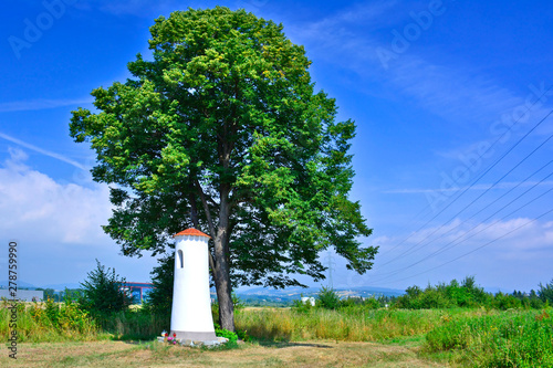 A small white chapel under tree in sunny summer day, Stary Sacz, Poland photo