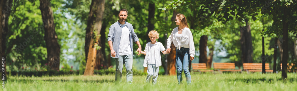 back view of family holding hands and running in park during daytime