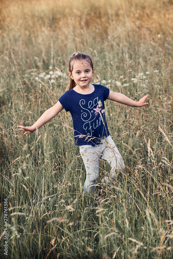 Little happy smiling kid playing in a tall grass in the countryside. Candid people, real moments, authentic situations Little happy smiling kid playing in a tall grass in the countryside. Candid people, real moments, authentic situations
