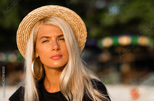 Portrait of a beautiful blonde wearing a straw hat. Modern woman. Travel around the world