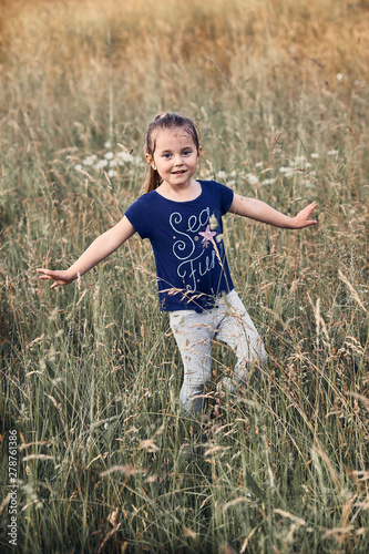 Little happy smiling kid playing in a tall grass in the countryside. Candid people, real moments, authentic situations © Przemek Klos