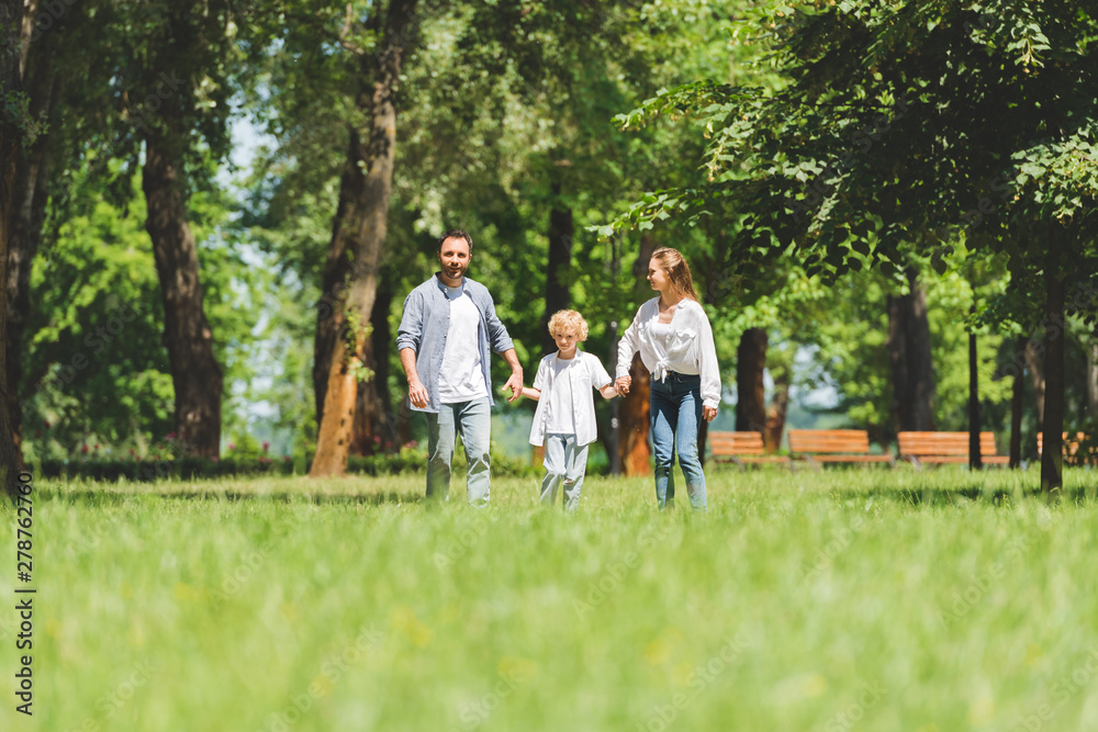Obraz premium selective focus of happy family holding hands and running in park during daytime