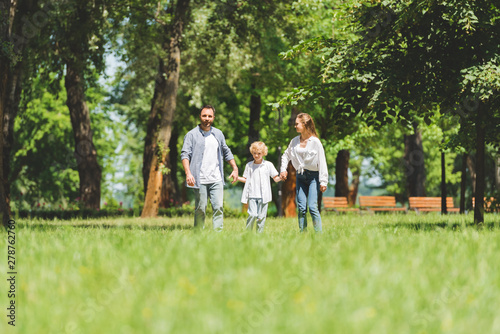 selective focus of happy family holding hands and running in park during daytime