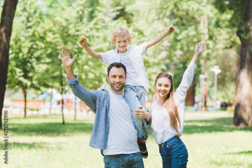 happy family with outstretched hands looking at camera in park