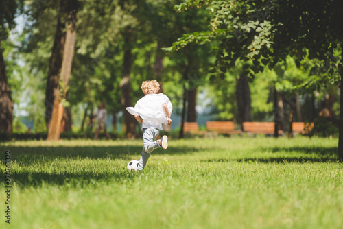 back view of boy playing football in park during daytime